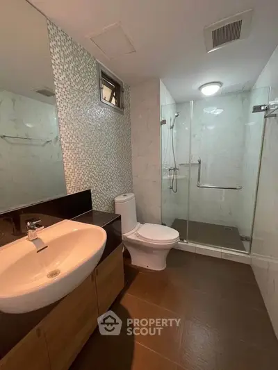 Modern bathroom with glass shower and stylish sink in a contemporary apartment.