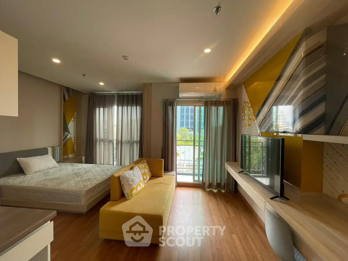 Modern studio apartment with stylish decor and large windows offering city views.