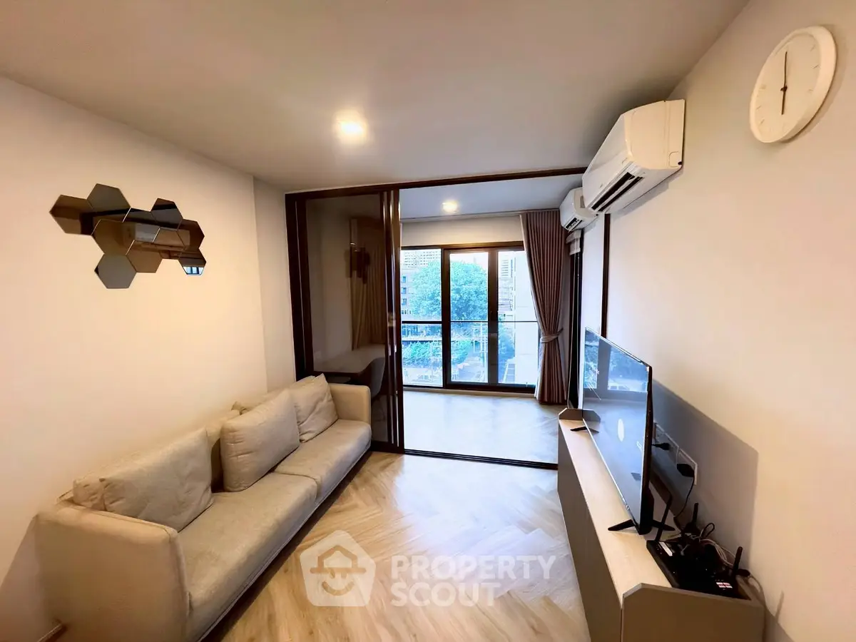 Modern living room with balcony view, featuring sleek furniture and stylish decor in a contemporary apartment.