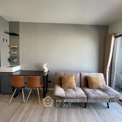 Modern living room with stylish sofa and dining area, featuring sleek design and neutral tones.