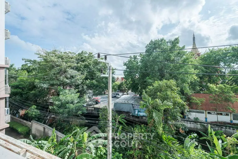 Scenic view from balcony overlooking lush greenery and urban landscape.