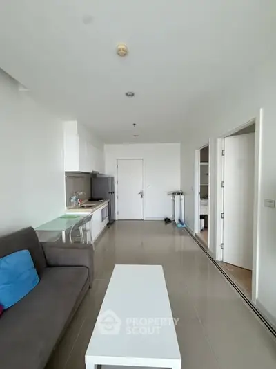 Modern living room with sleek furniture and open kitchen layout in a bright apartment.