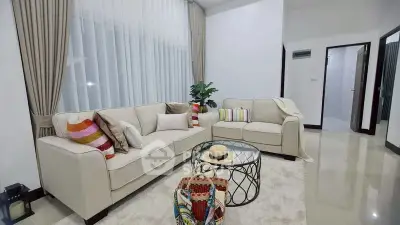 Elegant living room with modern beige sofas, stylish decor, and large windows for natural light.