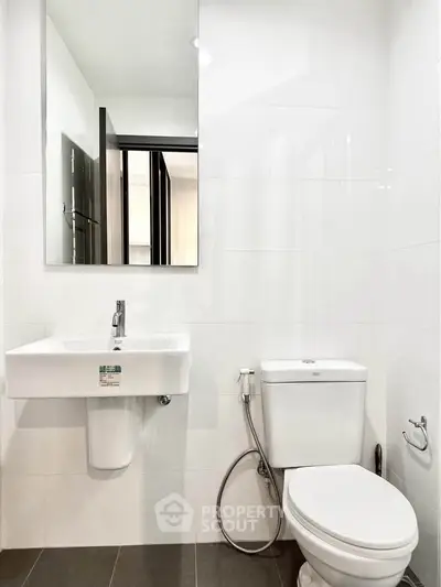 Modern bathroom with sleek fixtures and white tiles, featuring a wall-mounted sink and toilet.