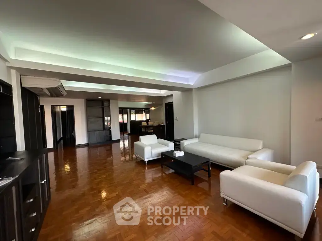 Spacious modern living room with sleek white furniture and wooden flooring