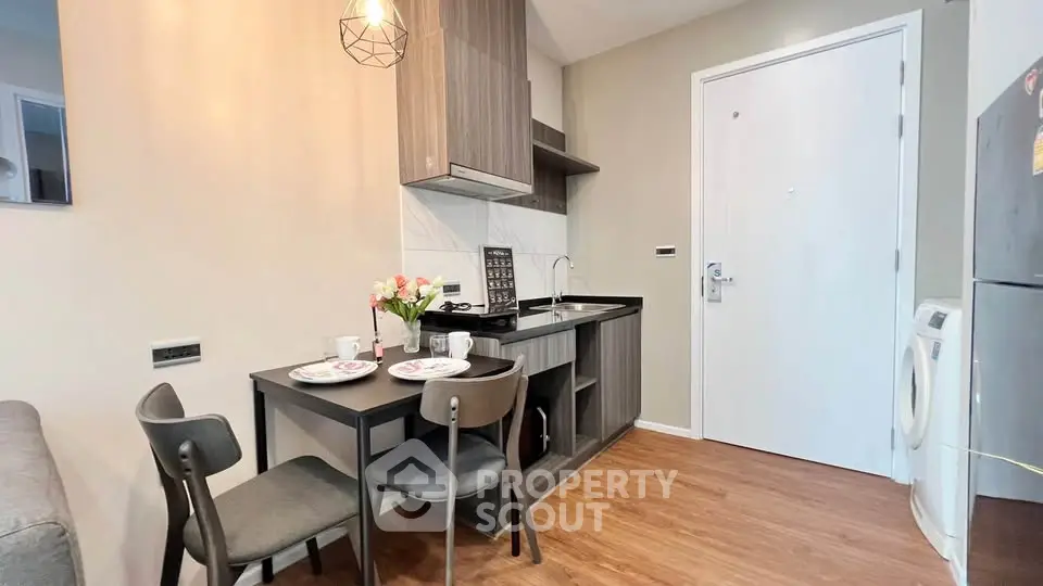 Modern kitchen with dining area in a cozy apartment, featuring sleek cabinetry and stylish lighting.