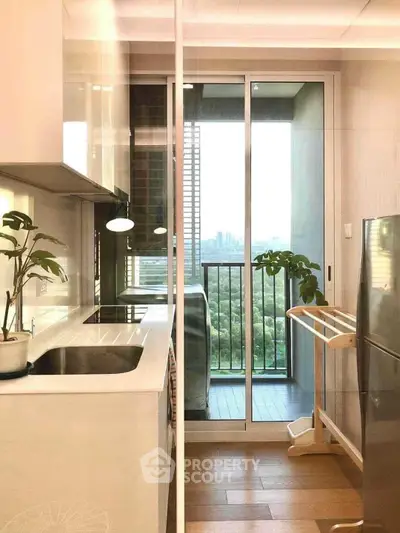 Modern kitchen with sleek design and balcony view, featuring stainless steel appliances and natural light.