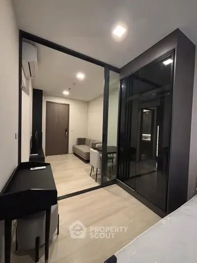 Modern apartment interior with sleek design and glass partition, featuring a cozy living area and stylish furniture.