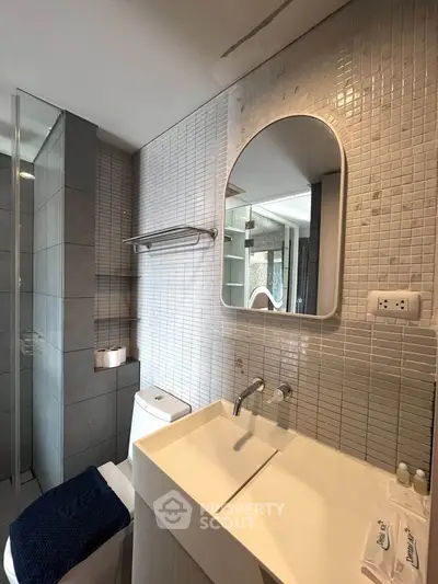 Modern bathroom with sleek fixtures and stylish tile design, featuring a large mirror and contemporary sink.
