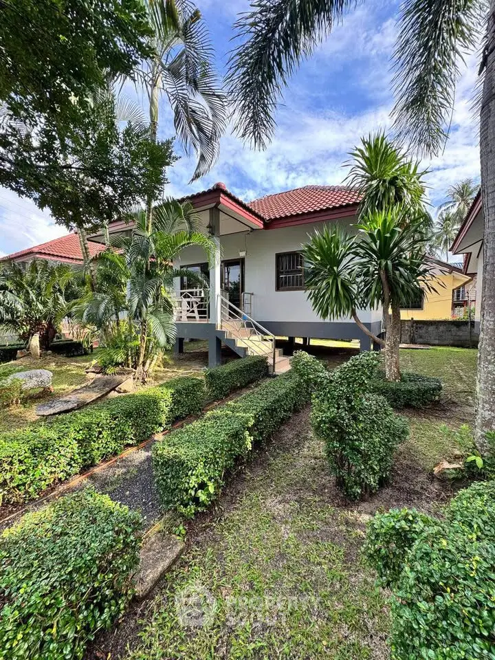 Charming tropical house with lush garden and red-tiled roof