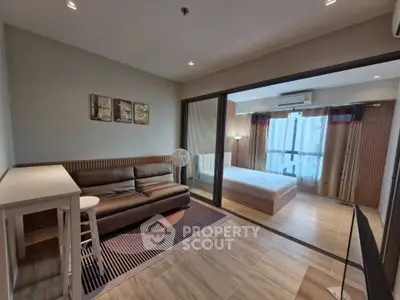 Modern open-layout living room with sliding doors to a cozy bedroom, featuring stylish decor and ample natural light.