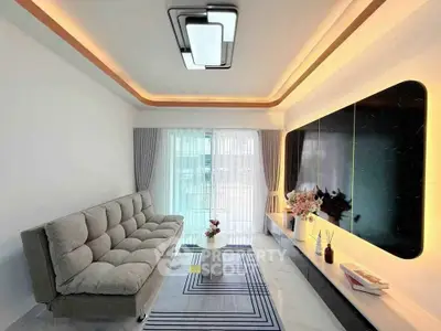Modern living room with stylish lighting and sleek furniture, featuring a large TV and elegant decor.