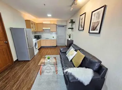 Modern open-layout living room with kitchen, featuring sleek furniture and stylish decor.