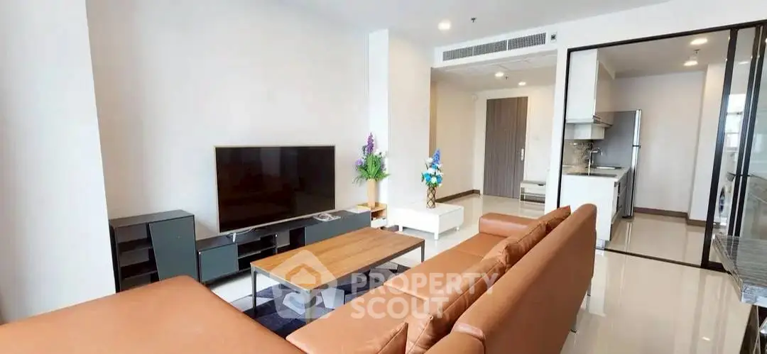 Spacious modern living room with sleek furniture and open kitchen layout.