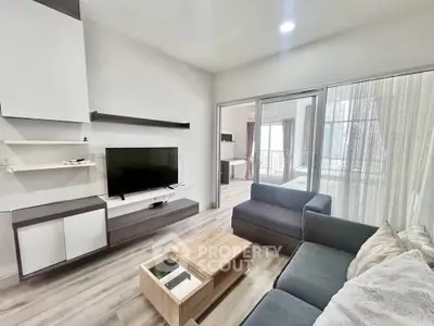 Modern living room with sleek furniture and natural light, featuring a cozy sofa and flat-screen TV.