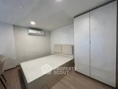 Modern minimalist bedroom with built-in wardrobe and air conditioning unit.