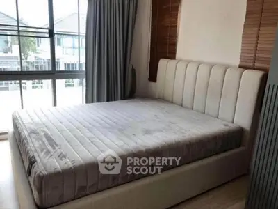 Spacious bedroom with large window and modern bed frame, offering ample natural light.