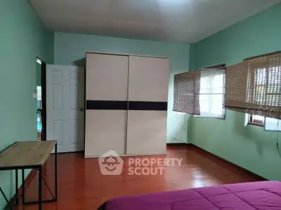 Spacious bedroom with wooden flooring and large wardrobe in a cozy home.