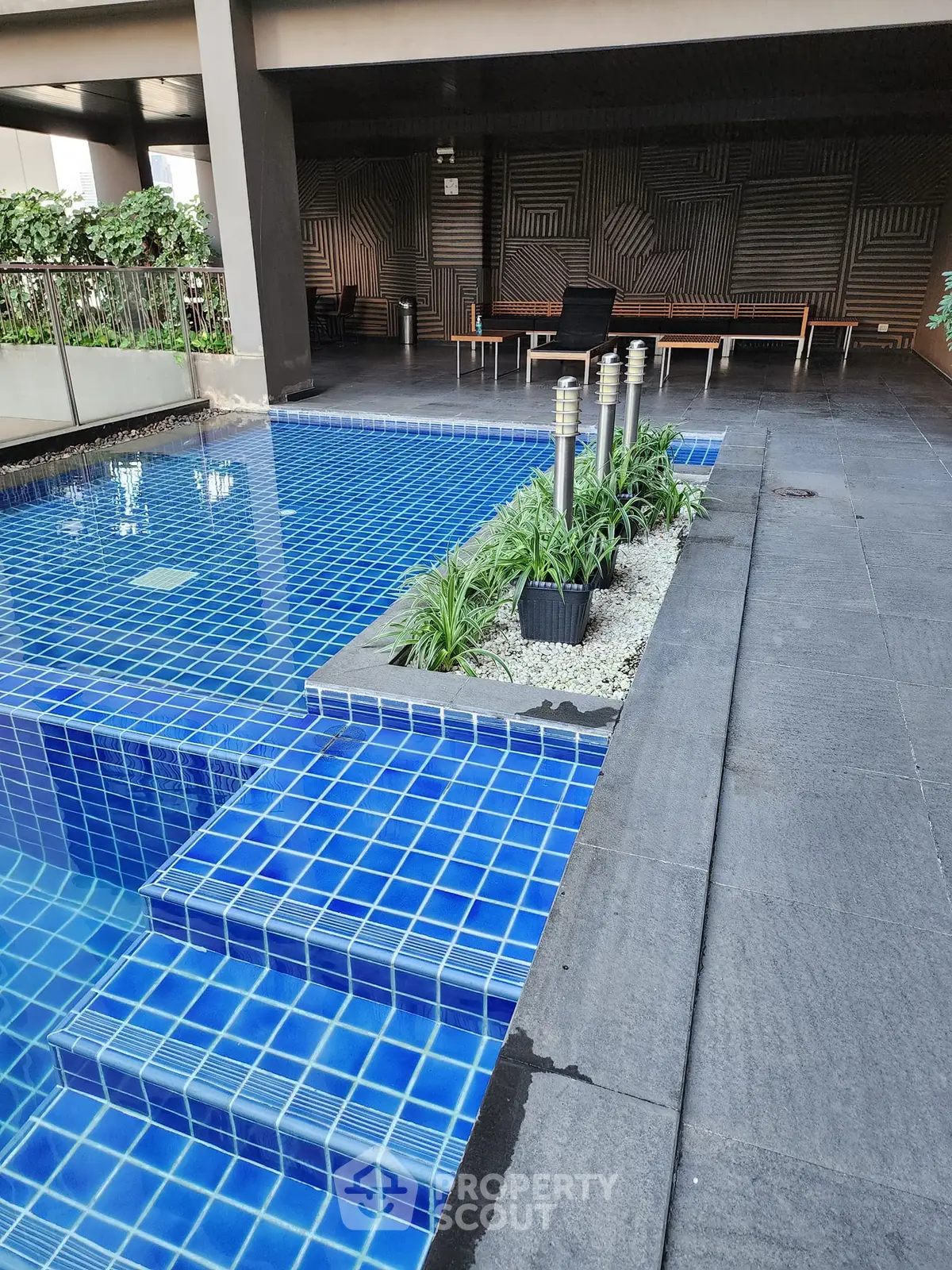 Luxurious modern pool area with sleek blue tiles and stylish seating, perfect for relaxation and leisure.