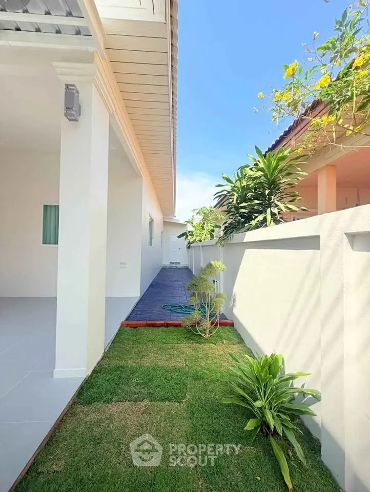 Charming side garden with lush greenery and modern exterior design, perfect for relaxation.