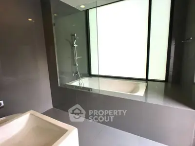 Modern bathroom with sleek design and large bathtub, featuring floor-to-ceiling window for natural light.