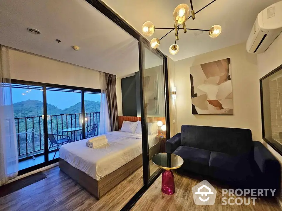 Modern bedroom with balcony and scenic mountain view, stylish decor and cozy seating area.