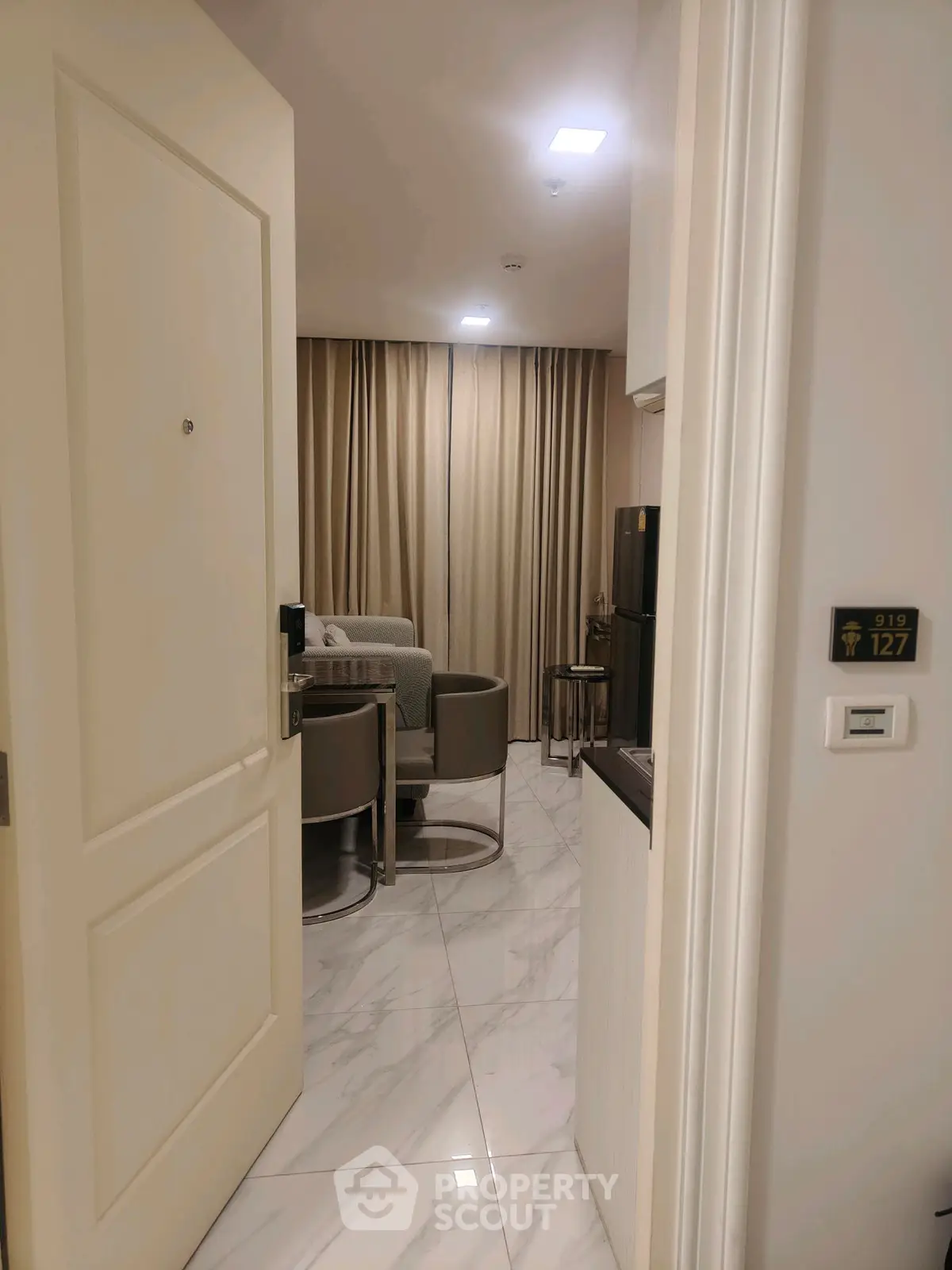 Modern apartment entrance leading to a stylish living room with elegant decor and marble flooring.