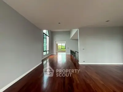 Spacious empty living room with hardwood floors and large windows.