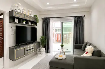 Modern living room with sleek TV unit, cozy sofa, and sliding glass doors leading to a balcony.