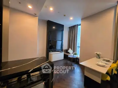 Modern living room with sleek design and natural light, featuring a TV and elegant decor.