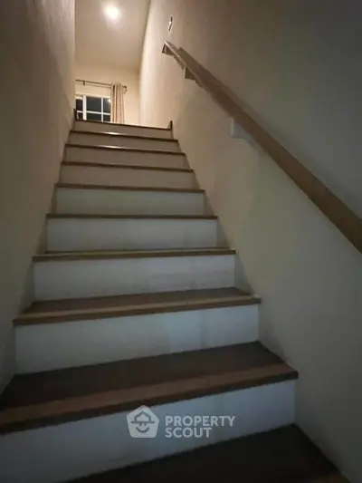Cozy staircase leading to upper floor with wooden handrail and soft lighting.