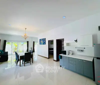 Spacious open-plan living and dining area with modern kitchen and elegant chandelier.