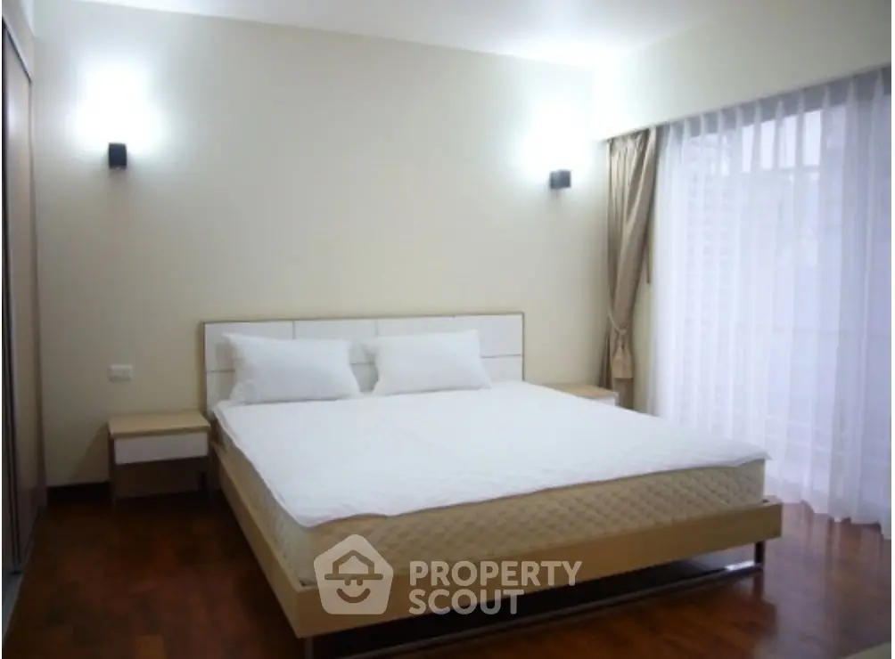 Spacious bedroom with modern decor and large window for natural light.