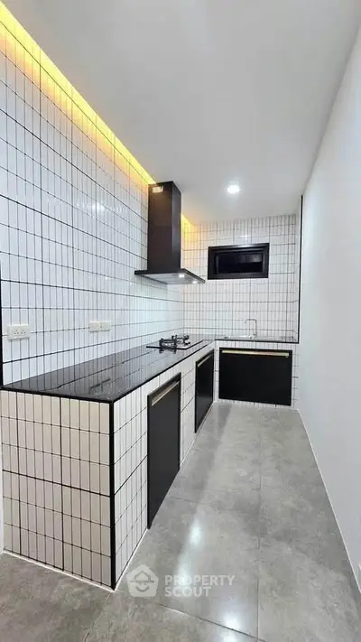 Modern kitchen with sleek black countertops and gas stove in a stylish tiled design.