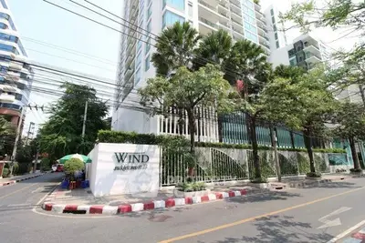 Modern condominium building with lush greenery and street view in vibrant urban setting.