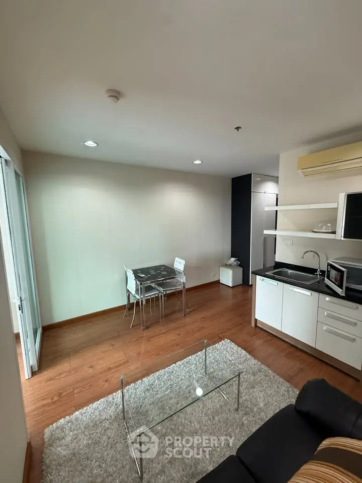 Modern living room with open kitchen, wooden flooring, and stylish furniture in a cozy apartment.