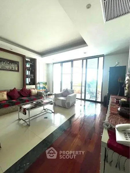 Spacious living room with elegant decor and large windows offering natural light and a view.
