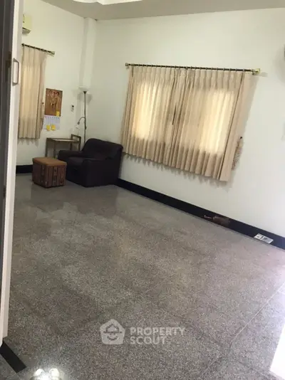Spacious room with armchair and large windows, perfect for versatile use.