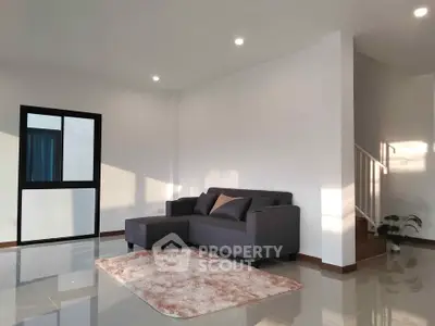 Modern living room with sleek gray sofa and plush rug in bright, minimalist interior.