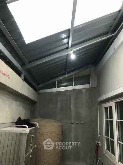Industrial-style utility room with metal roof and concrete walls, featuring a large water tank.