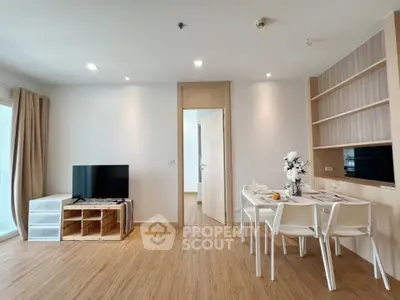 Modern living room with dining area and TV, featuring wooden flooring and minimalist decor.