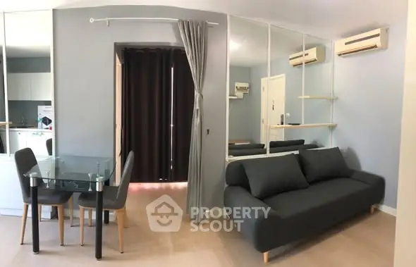 Modern living room with sleek sofa, glass dining table, and mirrored wall in stylish apartment.