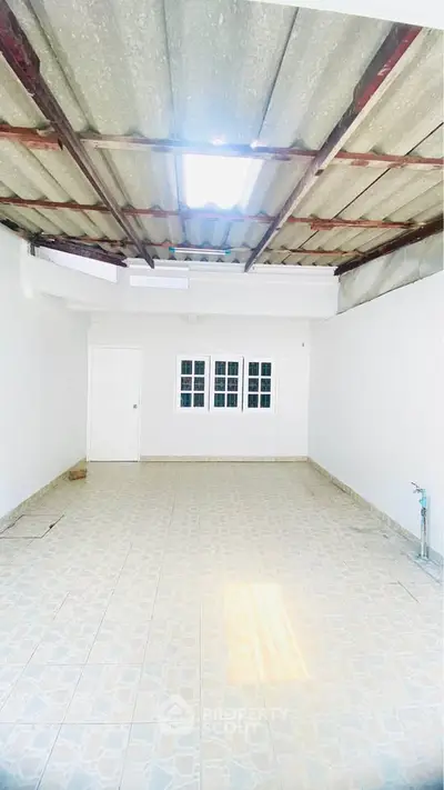 Spacious unfinished room with tiled floor and exposed ceiling, ideal for customization.