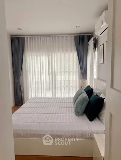 Cozy modern bedroom with large window and elegant curtains, featuring a comfortable double bed and stylish decor.