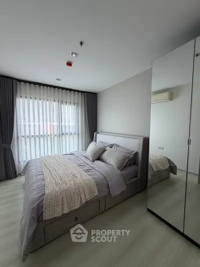 Modern bedroom with stylish decor and large mirrored wardrobe in a bright apartment.
