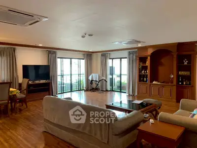 Spacious living room with wooden floors and large windows offering natural light