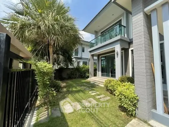 Modern two-story house with lush garden and glass balcony, perfect for family living.