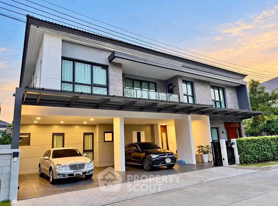 Luxurious modern two-story house with spacious driveway and elegant facade, featuring two parked cars.