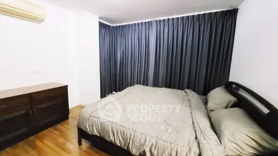 Cozy bedroom with elegant curtains and wooden flooring, featuring a comfortable bed and air conditioning.