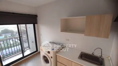 Modern laundry area with washing machine and balcony view in a stylish apartment.